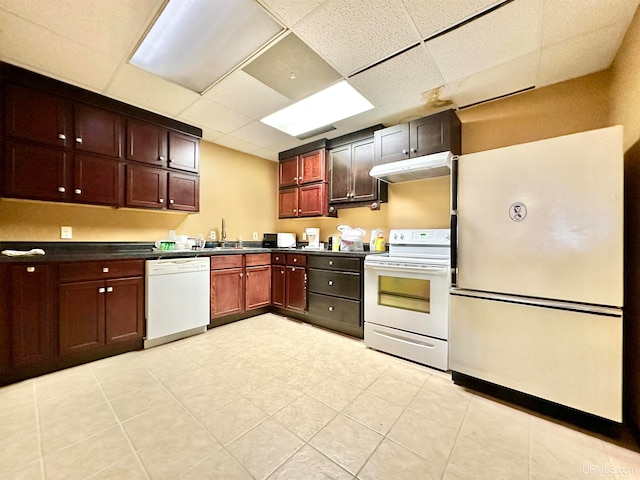 kitchen featuring sink, light tile patterned flooring, a paneled ceiling, and white appliances