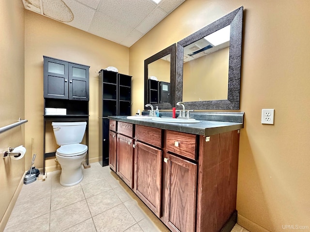 bathroom featuring vanity, a drop ceiling, toilet, and tile patterned flooring