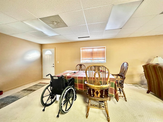 dining area featuring a paneled ceiling and carpet flooring