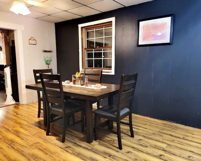 dining space featuring light hardwood / wood-style floors and a drop ceiling