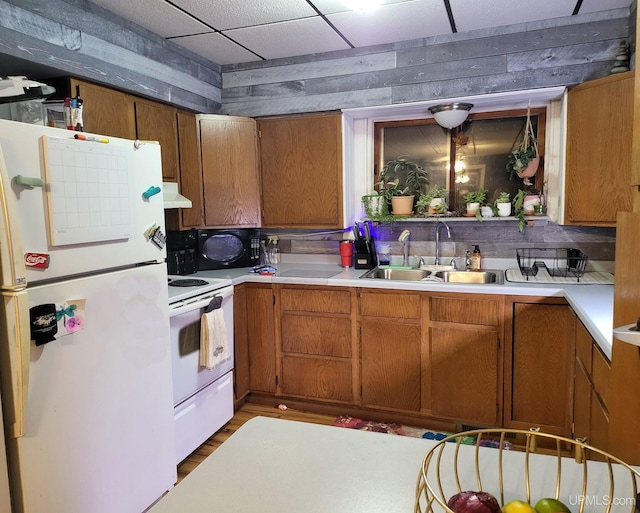 kitchen with white appliances, a paneled ceiling, sink, and hardwood / wood-style flooring