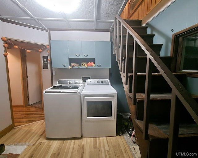 laundry area featuring separate washer and dryer, light hardwood / wood-style flooring, and cabinets