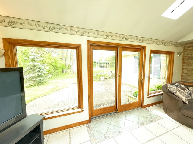 doorway to outside with vaulted ceiling with skylight and light tile patterned floors