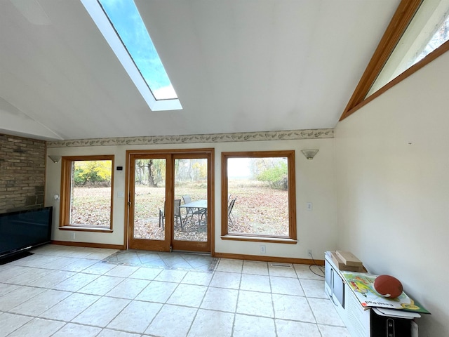 interior space with lofted ceiling with skylight and light tile patterned floors