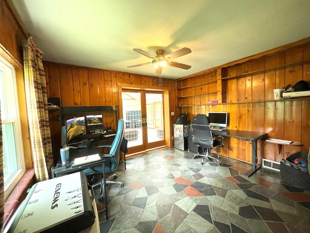 home office featuring ceiling fan, wood walls, a wealth of natural light, and french doors