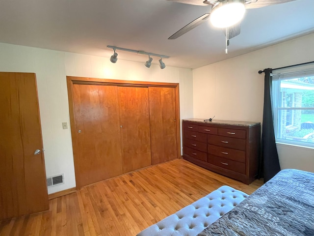 bedroom featuring rail lighting, a closet, light hardwood / wood-style flooring, and ceiling fan