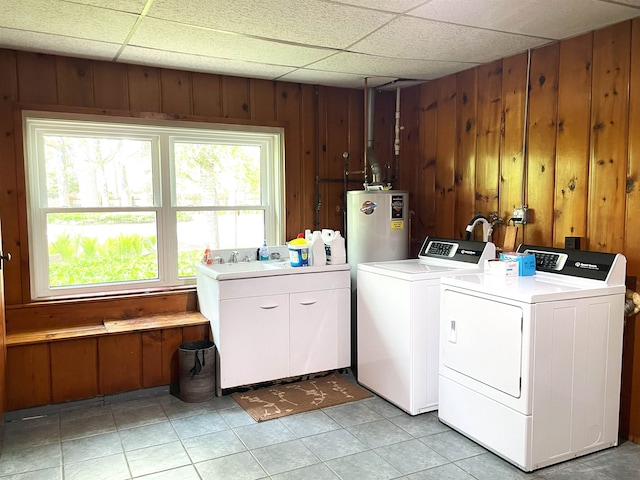 laundry area with wood walls, independent washer and dryer, a healthy amount of sunlight, and water heater