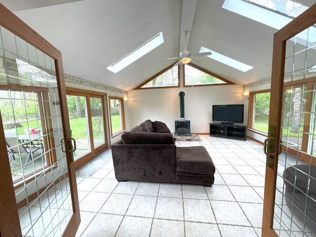 living room featuring lofted ceiling, ceiling fan, light tile patterned flooring, and a wood stove