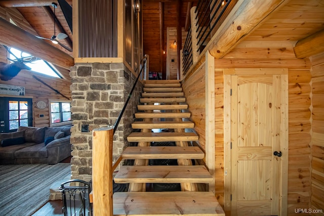 stairs featuring a skylight, hardwood / wood-style floors, ceiling fan, wooden ceiling, and rustic walls