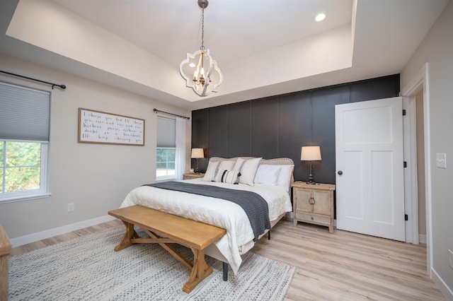 bedroom featuring multiple windows, a barn door, and light wood-type flooring