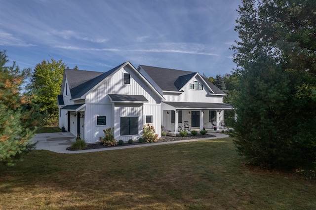 modern farmhouse featuring a front yard, covered porch, and a garage