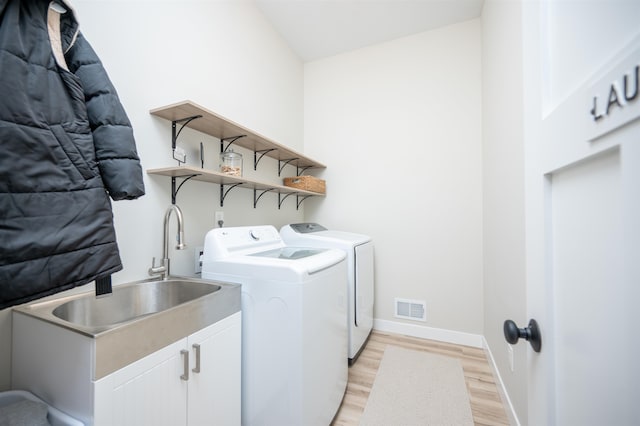 laundry area featuring light hardwood / wood-style floors, independent washer and dryer, and cabinets