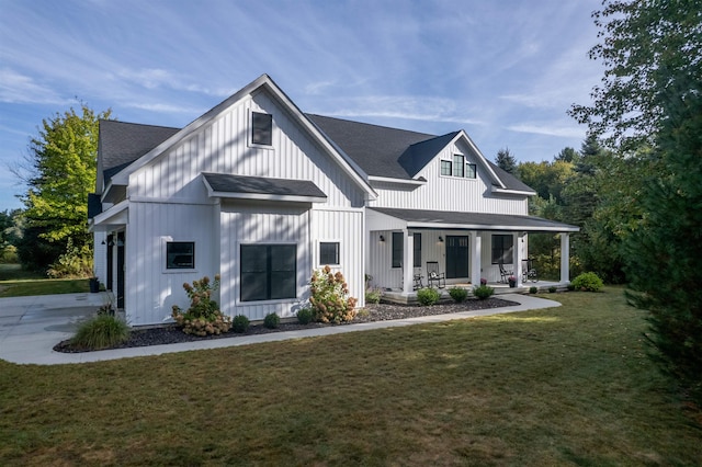 rear view of house with a garage, a lawn, and a porch