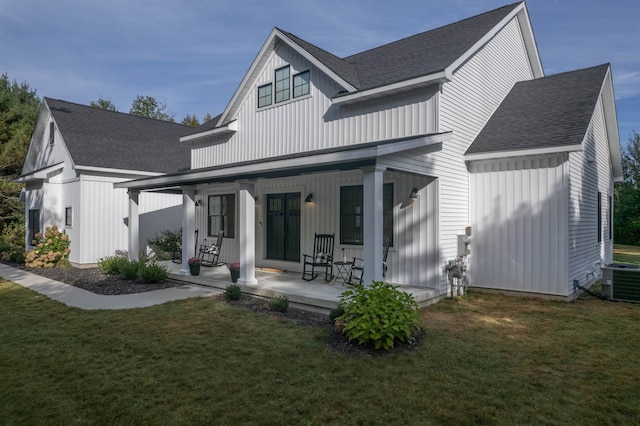 rear view of property featuring covered porch, a lawn, and central AC unit