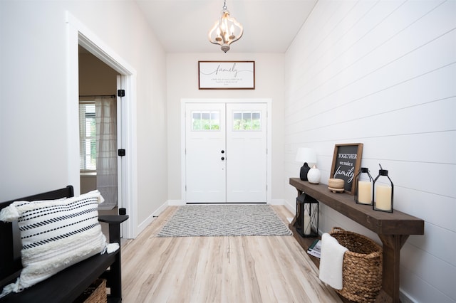 entryway with a wealth of natural light, a chandelier, and light wood-type flooring