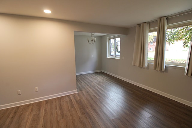 unfurnished room featuring a notable chandelier and dark hardwood / wood-style flooring