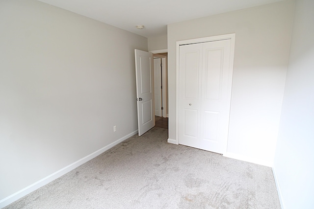 unfurnished bedroom featuring a closet and light colored carpet