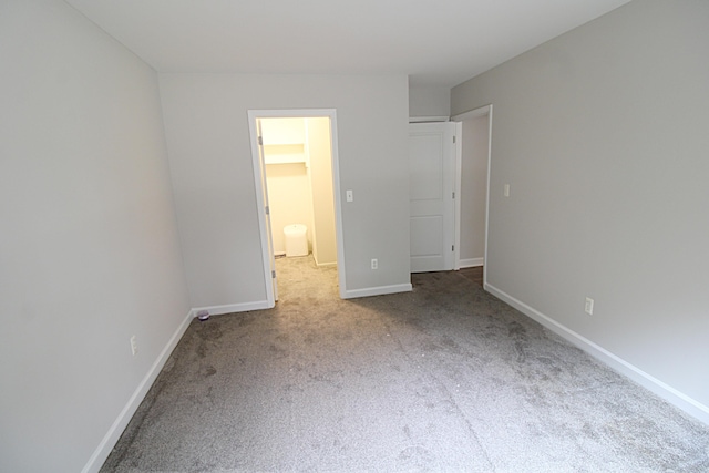 unfurnished bedroom with a spacious closet, a closet, and light colored carpet