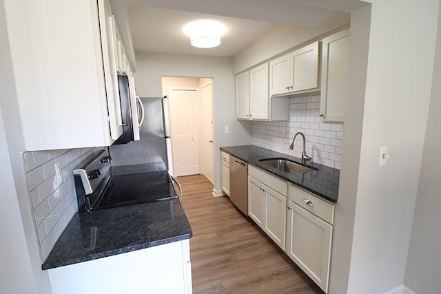 kitchen featuring sink, stainless steel appliances, white cabinets, decorative backsplash, and light hardwood / wood-style flooring