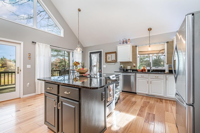 kitchen featuring white cabinets, a kitchen island, dark stone counters, light hardwood / wood-style floors, and stainless steel appliances