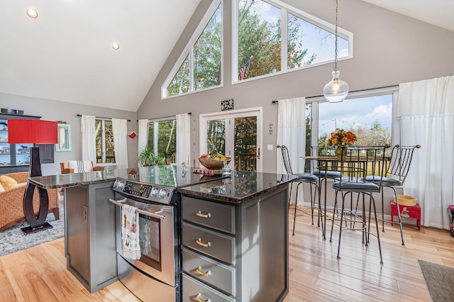 kitchen featuring light hardwood / wood-style flooring, stainless steel range with electric stovetop, a center island, pendant lighting, and high vaulted ceiling