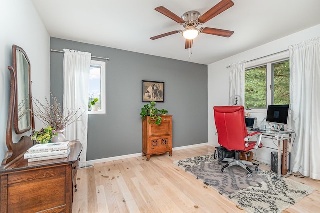 home office with a wealth of natural light, light hardwood / wood-style floors, and ceiling fan