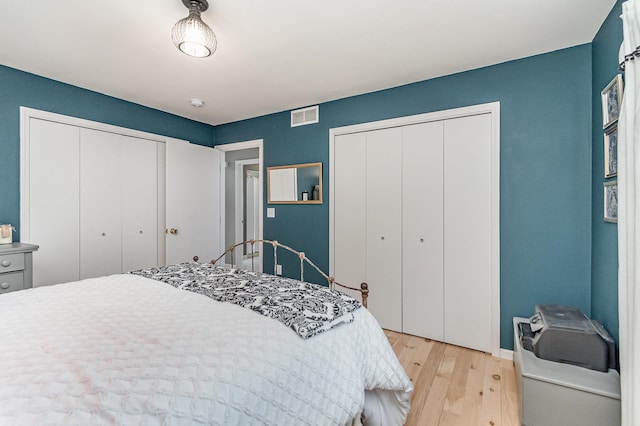 bedroom featuring two closets and light hardwood / wood-style floors