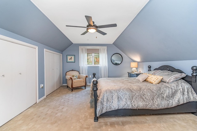 carpeted bedroom featuring lofted ceiling, multiple closets, and ceiling fan