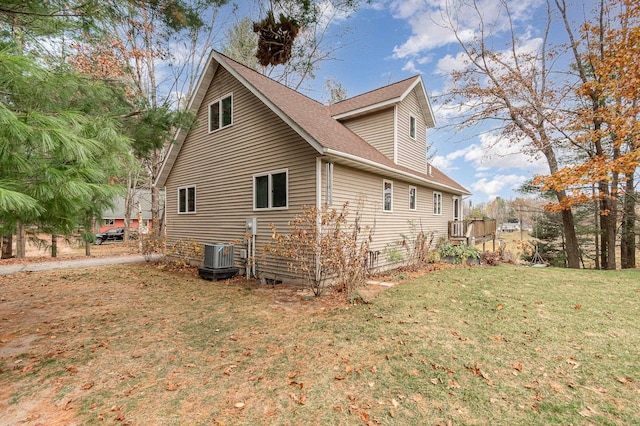 view of side of home with central AC and a yard