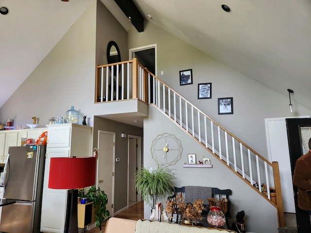 stairway with beamed ceiling, hardwood / wood-style flooring, and high vaulted ceiling