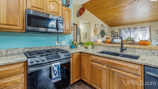 kitchen with sink, light stone countertops, stainless steel appliances, and vaulted ceiling