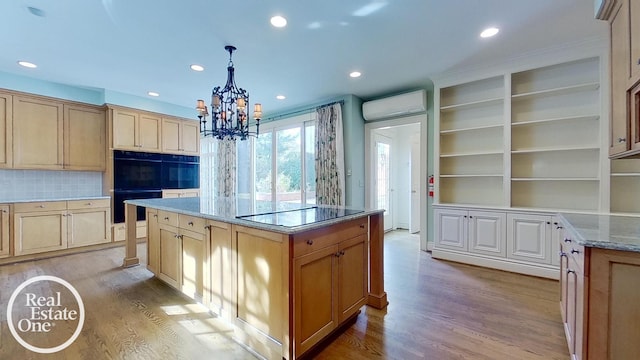 kitchen with a wall mounted air conditioner, a center island, hanging light fixtures, and light hardwood / wood-style floors