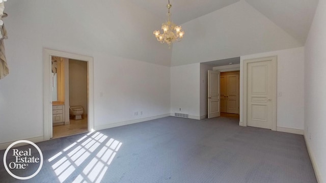 unfurnished bedroom with ensuite bath, a notable chandelier, carpet, and high vaulted ceiling