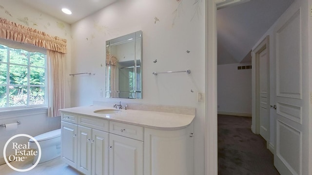 bathroom featuring vanity, toilet, and vaulted ceiling