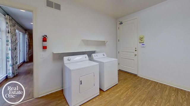 laundry room with light hardwood / wood-style flooring and washer and dryer