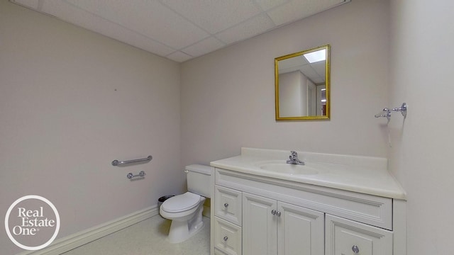 bathroom featuring vanity, a drop ceiling, and toilet