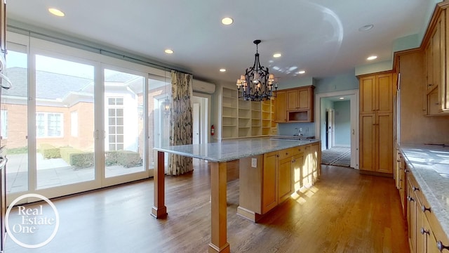 kitchen featuring a breakfast bar area, a kitchen island, light stone countertops, and hanging light fixtures