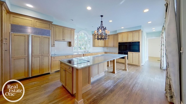 kitchen featuring tasteful backsplash, light wood-type flooring, black appliances, pendant lighting, and a center island