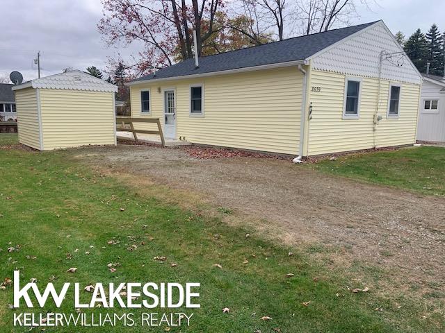 back of house with a storage shed and a yard