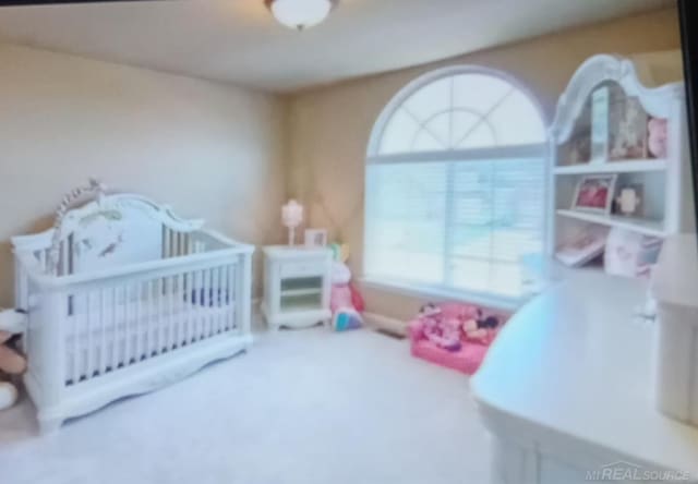 carpeted bedroom featuring a nursery area