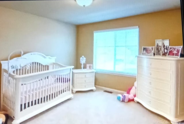 carpeted bedroom featuring a nursery area