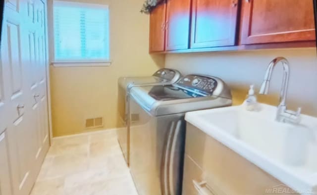 clothes washing area featuring washer and dryer and cabinets