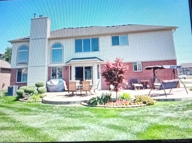 back of property with a yard, cooling unit, and a patio area