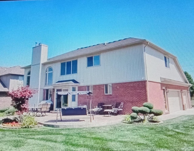 rear view of house featuring a yard, a garage, and a patio