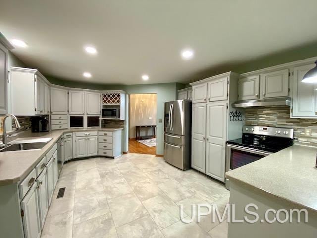 kitchen featuring white cabinets, appliances with stainless steel finishes, backsplash, and sink