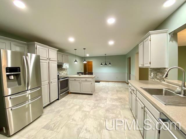 kitchen with sink, tasteful backsplash, kitchen peninsula, pendant lighting, and appliances with stainless steel finishes