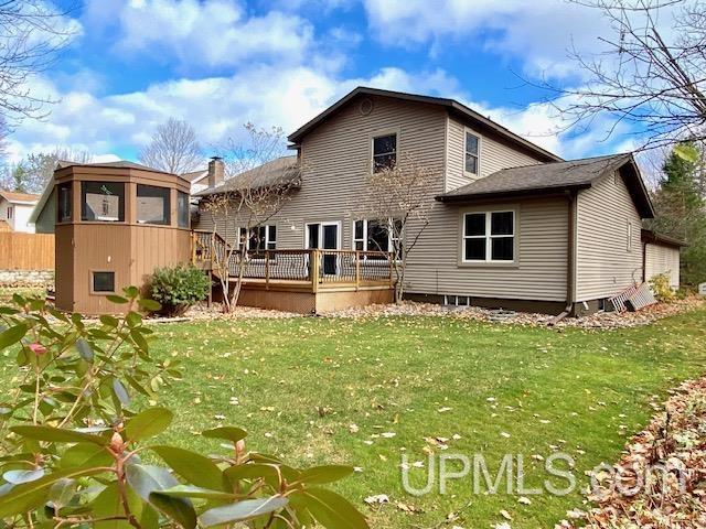 back of house featuring a sunroom, a deck, and a yard