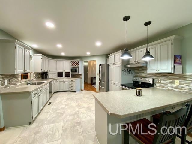 kitchen featuring kitchen peninsula, stainless steel appliances, hanging light fixtures, and sink