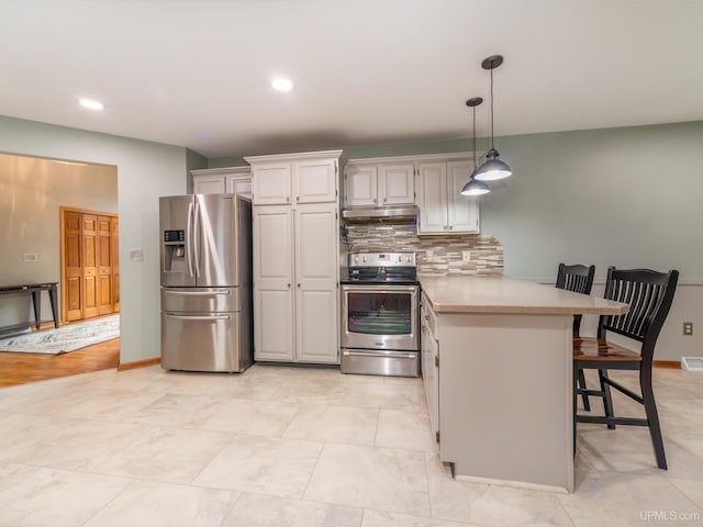 kitchen with kitchen peninsula, backsplash, stainless steel appliances, white cabinetry, and a breakfast bar area