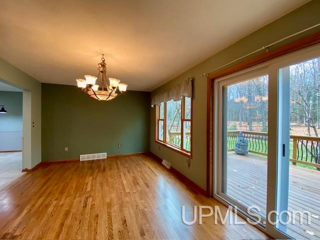 unfurnished dining area with light hardwood / wood-style flooring and an inviting chandelier